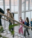 Studerende går op ad en trappe i en moderne universitetsbygning med store vinduespartier og masser af dagslys.